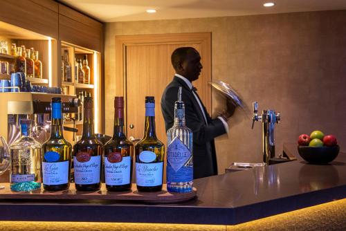 a man in a suit standing behind a counter with wine bottles at Radisson Blu Hotel, Rouen Centre in Rouen
