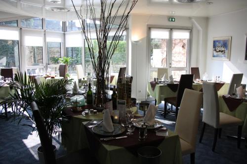 a dining room with tables and chairs and windows at La Berteliere, The Originals Relais in Saint-Martin-du-Vivier