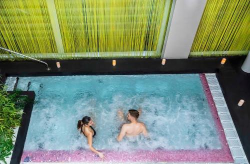 a man and a woman in a swimming pool at Hotel Kaj in Marija Bistrica