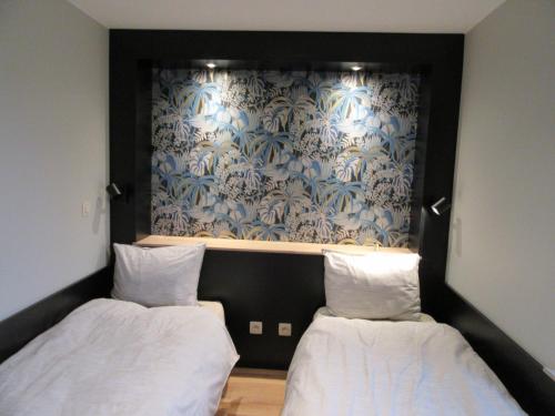 two beds in a room with a blue and white wallpaper at Gite du Circuit in Stavelot