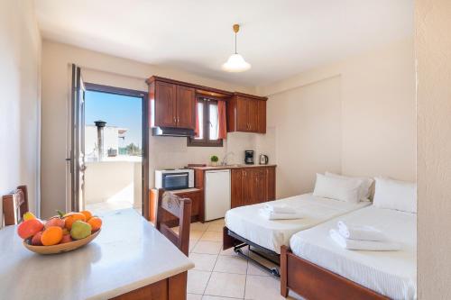 una habitación con 2 camas y una mesa con un bol de fruta en Lemon Tree Corfu Apartments by Konnect, en Ýpsos
