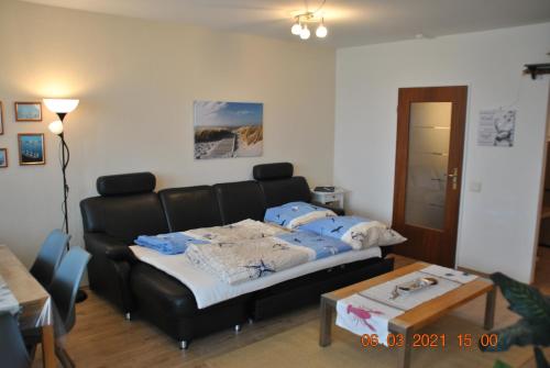 a living room with a black couch and a table at Apartment Meerblick in Bremerhaven