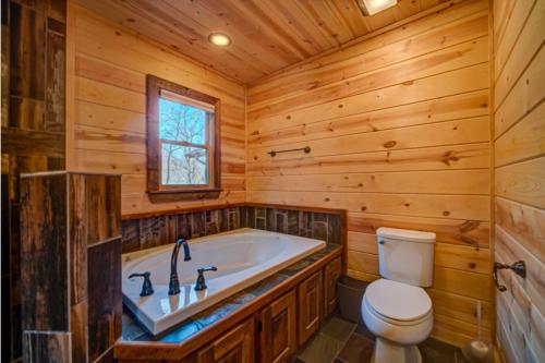 a log cabin bathroom with a tub and a toilet at The Hideaway in Blue Ridge