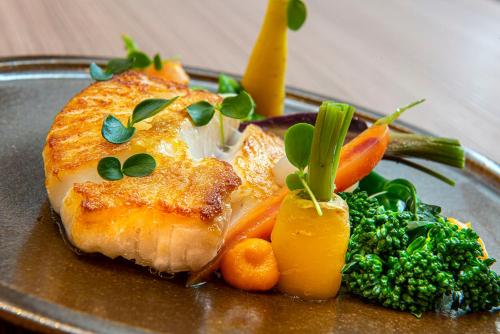 a plate of food with a piece of fish and vegetables at Radisson Blu Hotel, Rouen Centre in Rouen