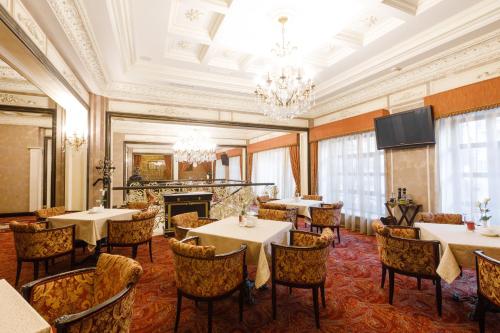una sala da pranzo con tavoli, sedie e lampadario a braccio di Axelhof Boutique Hotel a Dnipro