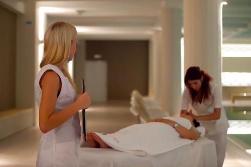 two women standing next to a woman laying on a bed at Kipriotis Village Resort in Kos Town