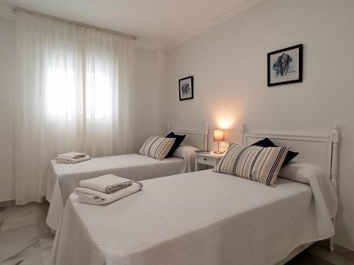 two beds in a white room with a window at Apartamento Sea Views Las Redes in El Puerto de Santa María