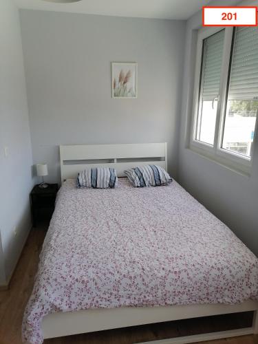 a white bedroom with a bed with a window at Immoappart in Albi