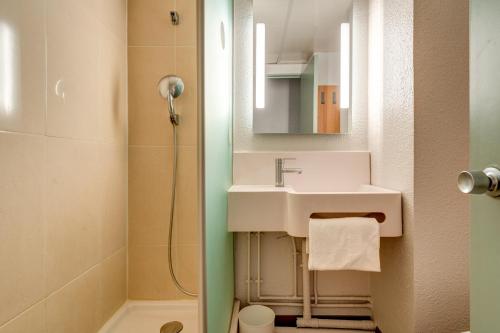 La salle de bains est pourvue d'un lavabo et d'une douche. dans l'établissement B&B HOTEL Orly Rungis Aéroport 2 étoiles, à Rungis