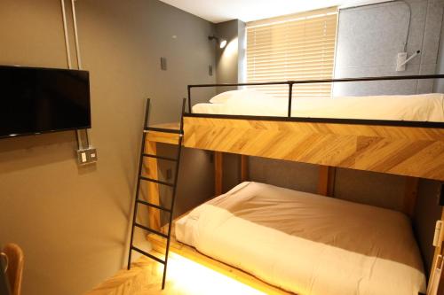 a room with two bunk beds and a flat screen tv at ZONK HOTEL Haruyoshi-Teramachidori in Fukuoka