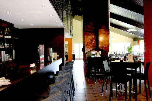 a restaurant with a bar with tables and chairs at La Berteliere, The Originals Relais in Saint-Martin-du-Vivier