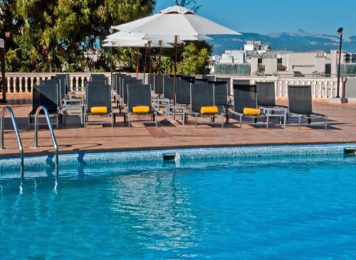 a swimming pool with chairs and an umbrella at BQ Augusta Hotel in Palma de Mallorca