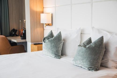 a bedroom with a bed with three pillows on it at Van der Valk Hotel Tiel in Tiel