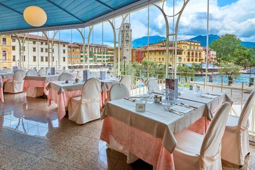 a room with tables and chairs with a view of a city at Hotel Europa - Skypool & Panorama in Riva del Garda