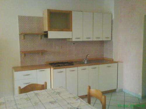 a kitchen with white cabinets and a table with chairs at Miramare Isola Rossa in Isola Rossa
