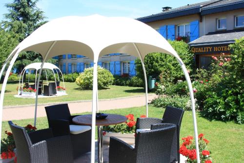 a table and chairs under a white umbrella at La Berteliere, The Originals Relais in Saint-Martin-du-Vivier