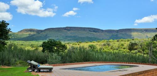 a swimming pool with mountains in the background at African Hills Safari Lodge & Spa in Magaliesburg