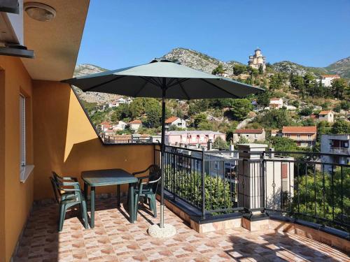 a patio with a table and an umbrella on a balcony at Apartman Nidžo in Trebinje