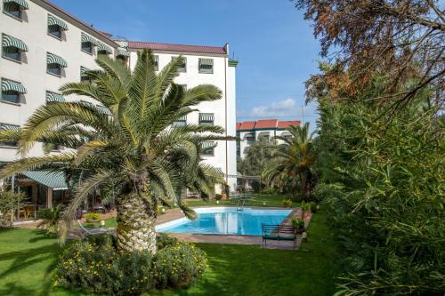 a palm tree in front of a building with a swimming pool at Best Western Park Hotel Roma Nord in Fiano Romano