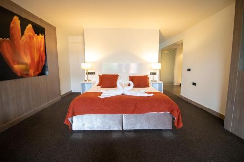 a bedroom with a large bed with a red blanket at Van der Valk Hotel Nuland - 's-Hertogenbosch in Nuland