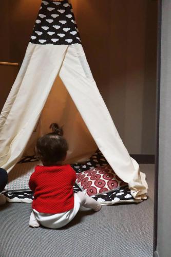 a child sitting on the floor next to a play tent at Alexandra in Lyon