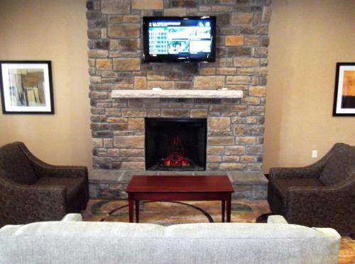 a living room with a stone fireplace with a tv at Stanton Inn and Suites in Stanton