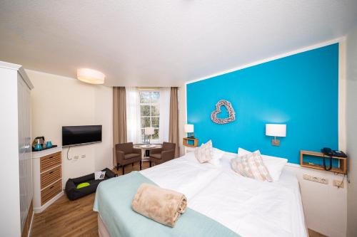 a bedroom with a large bed with a blue wall at Hotel kleine Auszeit - Adults Only in Sankt Peter-Ording