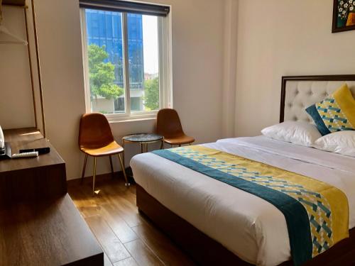 a bedroom with a bed and two chairs and a window at Swan Hotel in Ho Chi Minh City