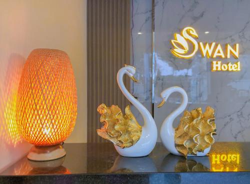 two swan sculptures and a lamp on a table at Swan Hotel in Ho Chi Minh City
