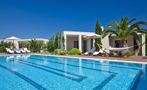 a swimming pool in front of a villa at Kipriotis Village Resort in Kos Town