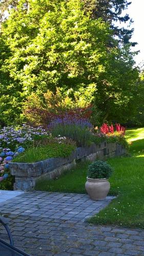 un jardín con flores y una pared de piedra en L'Aubergine, en Sprimont