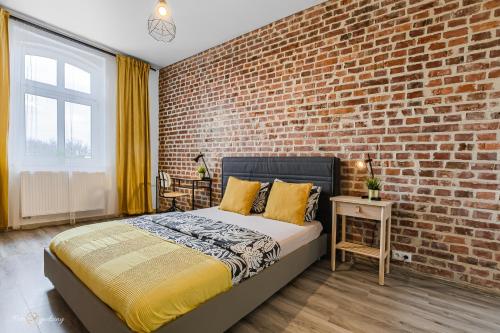 Un dormitorio con una pared de ladrillo y una cama. en UNO Apartaments, en Katowice