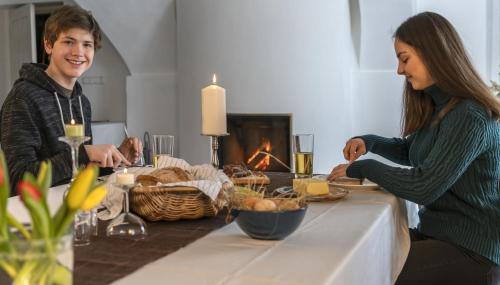 Ein Mann und eine Frau sitzen an einem Tisch und essen in der Unterkunft Grünsteinhof - Wohnung Rotstein in Ebersbach-Neugersdorf