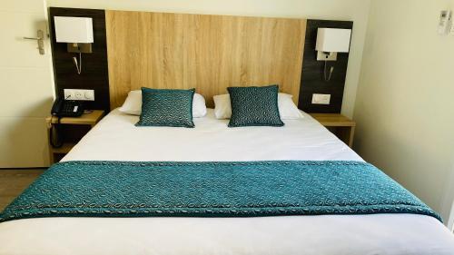 a bedroom with a large bed with blue pillows at Hotel Martinez Grenay in Grenay