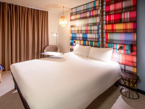 a bedroom with a large white bed and a colorful wall at ibis Styles Perpignan Centre Gare in Perpignan