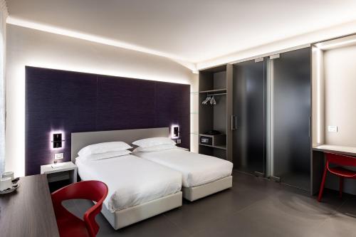 a bedroom with a large white bed and a red chair at RB del Teatro&Apartaments in Imola