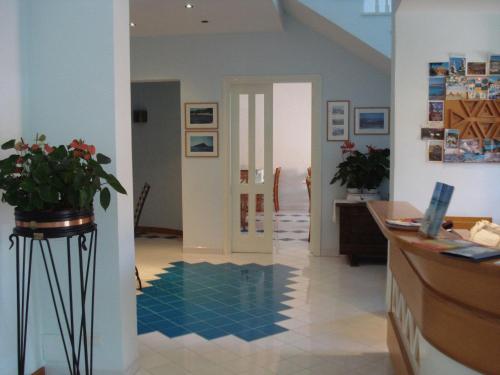 a room with a hallway with blue tiles on the floor at Hotel La Lampara in Golfo Aranci