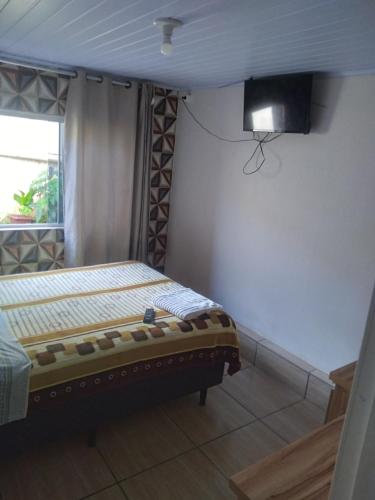 1 dormitorio con 1 cama y TV en la pared en JH santos, en Chapecó