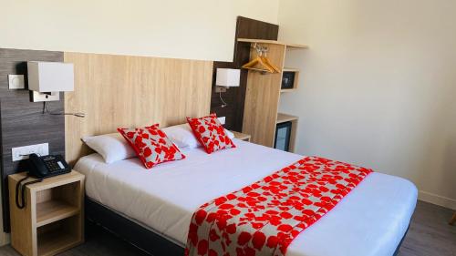 a bedroom with a large bed with red and white pillows at Hotel Martinez Grenay in Grenay
