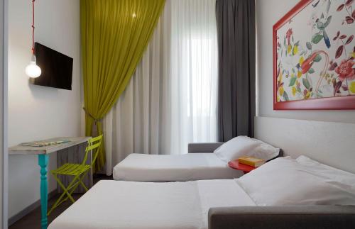 una camera d'albergo con due letti e un tavolo di Hotel Madison a Rimini