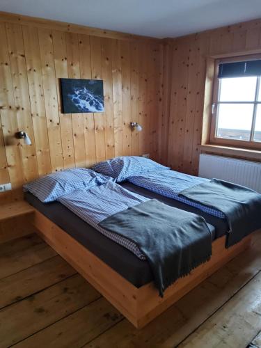 a bed in a room with a wooden wall at Fasserhof in Bramberg am Wildkogel