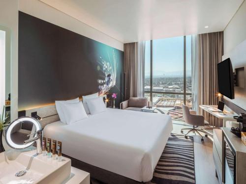 a hotel room with a large white bed and a desk at Novotel Mexico City Toreo in Mexico City