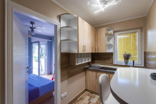 a kitchen with wooden cabinets and a blue bed at Sofia's Apartments in Biograd na Moru