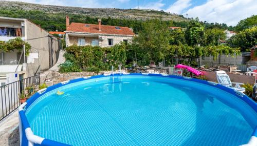 una gran piscina azul frente a una casa en Apartments Nicol, en Dubrovnik