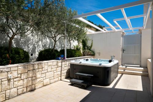 a hot tub in a backyard with a stone wall at Apartments Villa Azzurra Bol in Bol