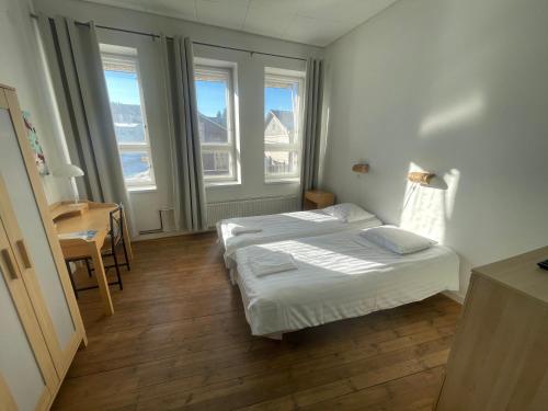 a bedroom with two beds and a table and windows at Jugend Boutique Guesthome in Pietarsaari