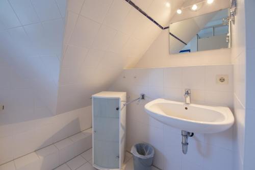 ミデルハーゲンにあるFerienwohnung Mohnblume - Strandhaus Lobbeの洗面台と鏡のある白いバスルーム