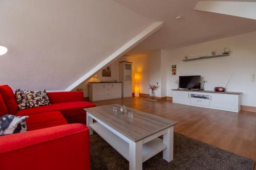 Sala de estar con sofá rojo y mesa de centro en Ferienwohnung Mohnblume - Strandhaus Lobbe, en Middelhagen