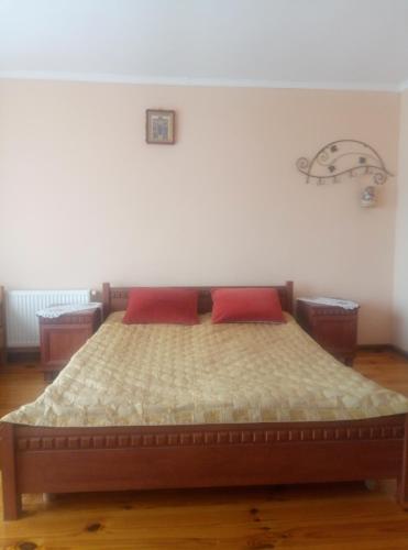 a bedroom with a bed with two red pillows at Park House in Pochayiv