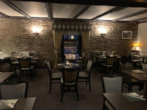 a restaurant with tables and chairs and a stone wall at Lion and Unicorn Hotel in Thornhill